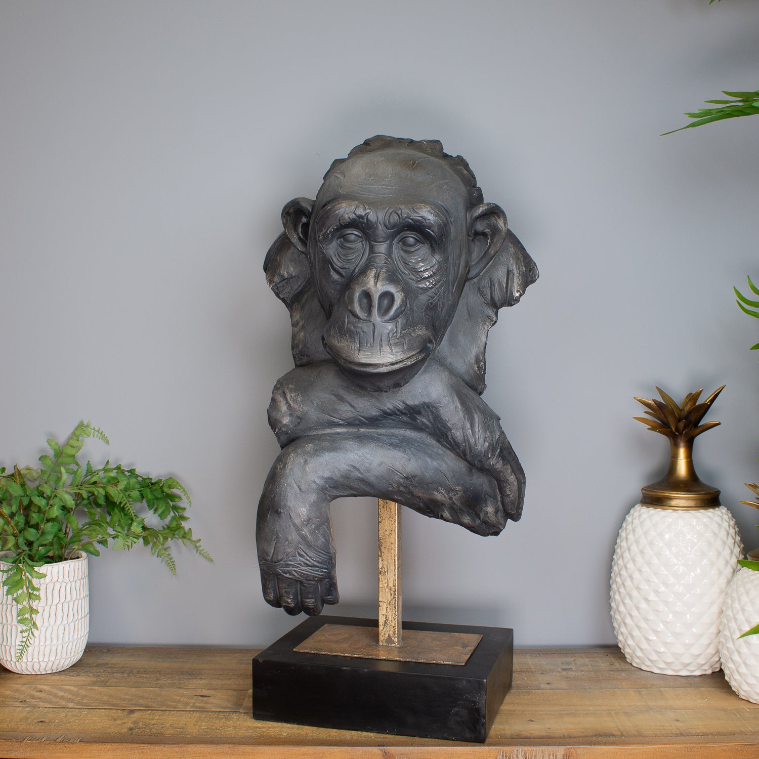 Monkey statue on a stand with decorative items in the background