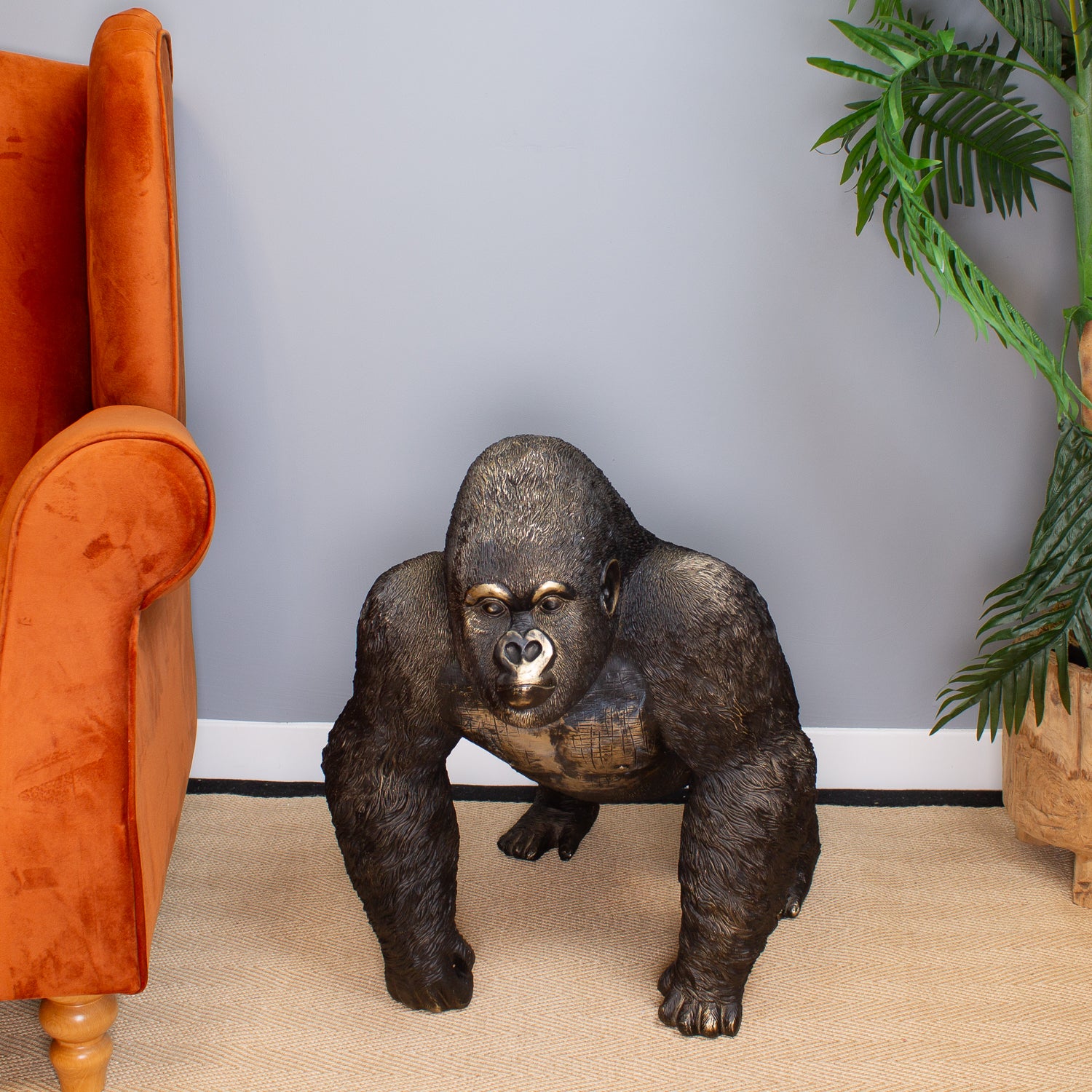 Gorilla statue in a room with an orange armchair and a plant.