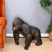 Statue of a gorilla in a room with an orange chair and plant