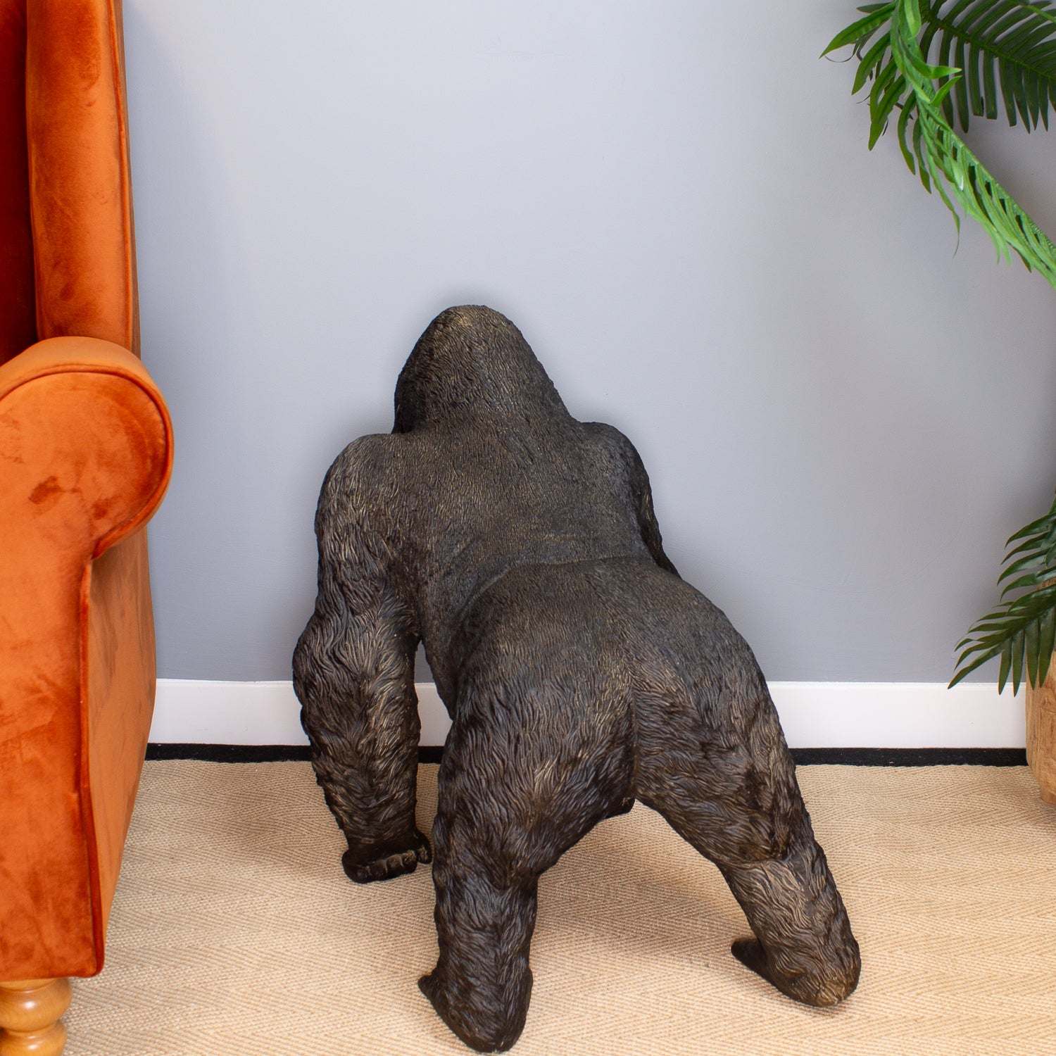 Gorilla statue in a room with an orange chair and plants.