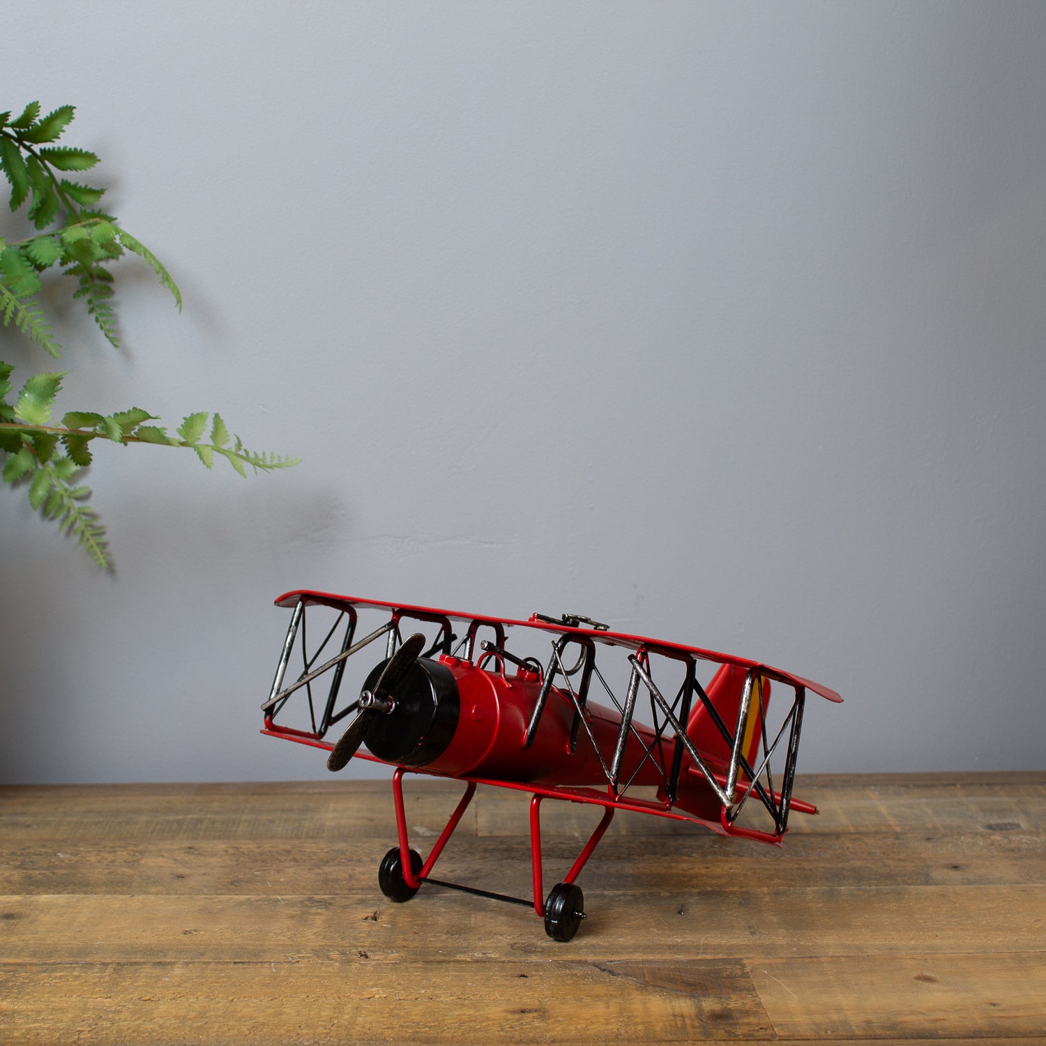 Red model airplane on a wooden surface with a gray background